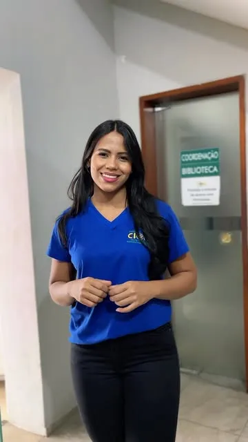 Colaboradora do Cierpi, com a camisa azul da escola, na porta da coordenação e da biblioteca